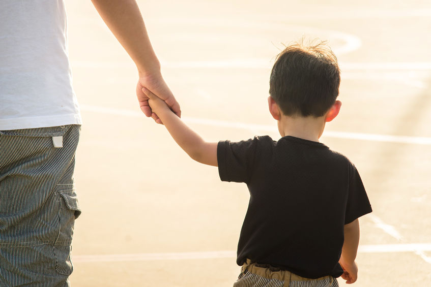 Father's hand leading his child son under sun light